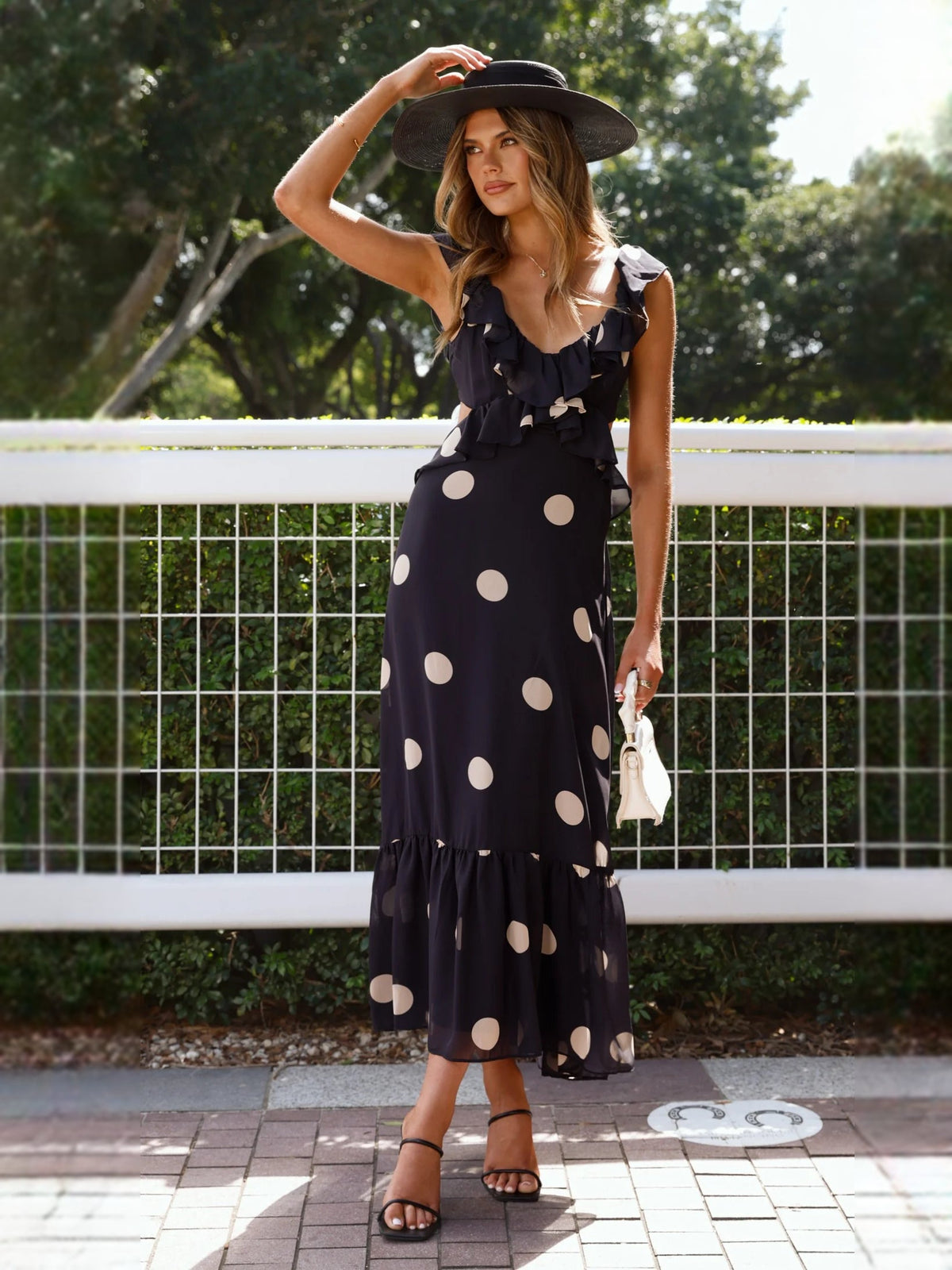 Black polka-dot midi dress with ruffled sleeveless bodice and flowy tiered hem