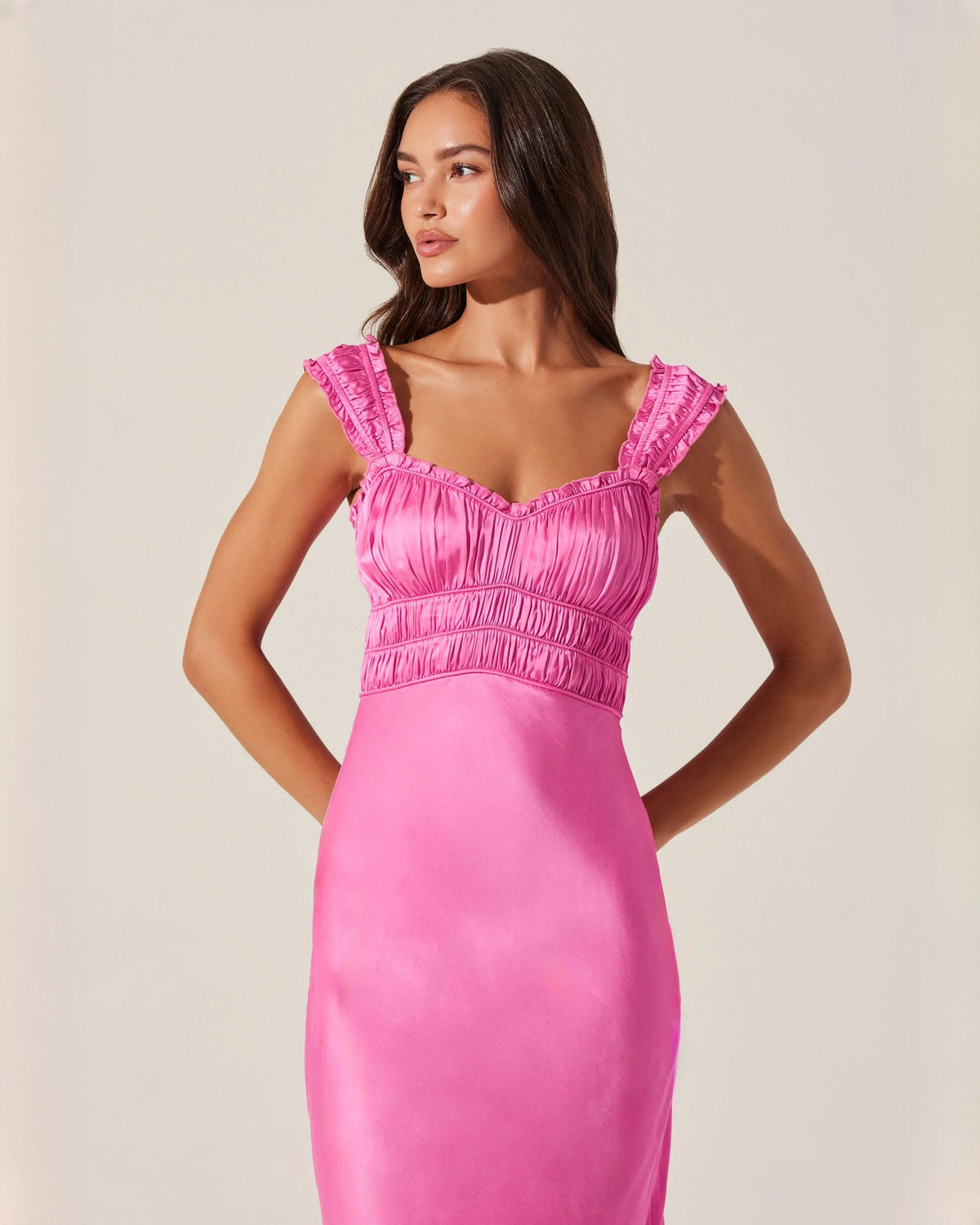 Pink sleeveless satin midi dress with smocked bodice and ruffle-edge shoulder straps.
