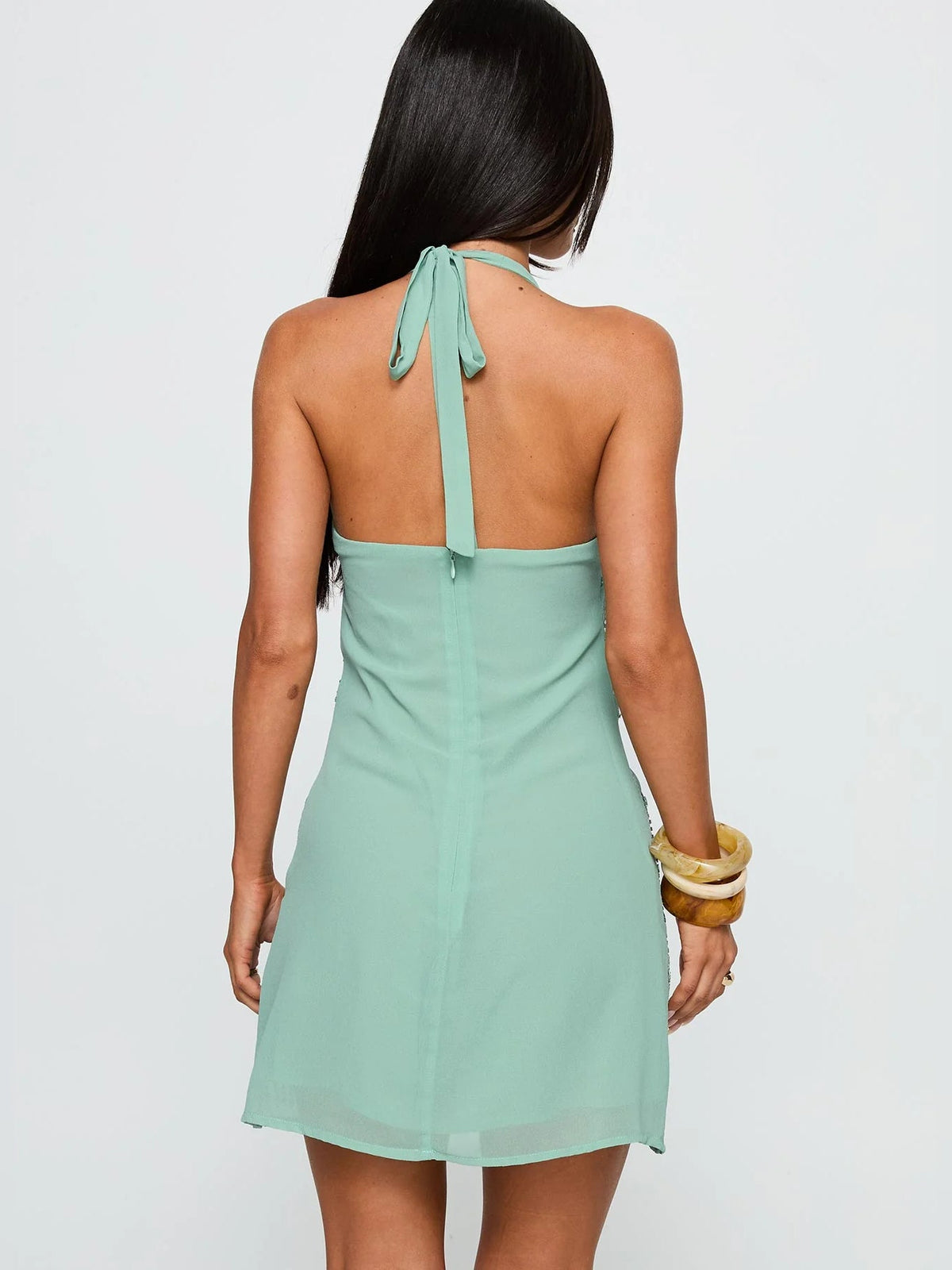 Back view of light teal halter neck mini dress with tied open-back strap