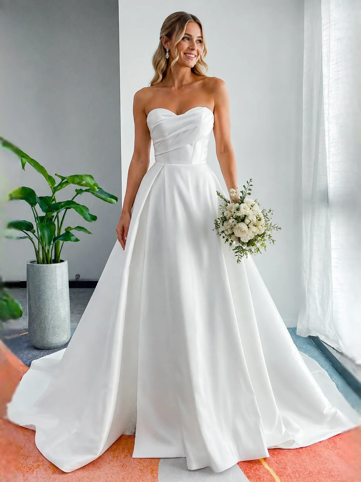 White strapless sweetheart satin A-line wedding dress on model holding bouquet, floor length