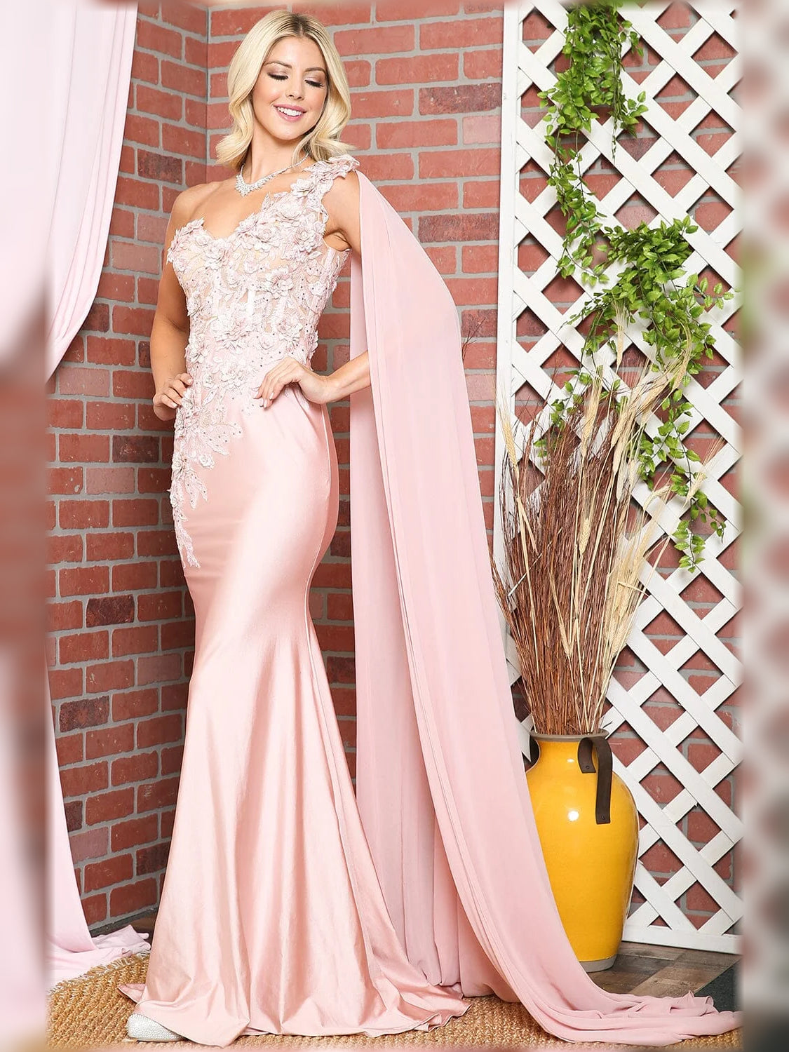 One-shoulder mermaid formal dress in blush pink with floral lace bodice and long drape.