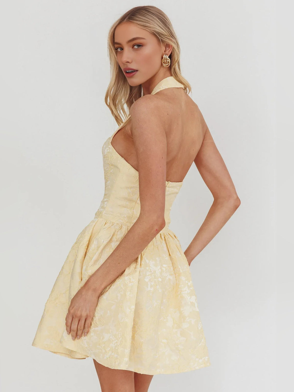 Pale lemon halter-neck corset mini dress with flared A-line skirt and open back