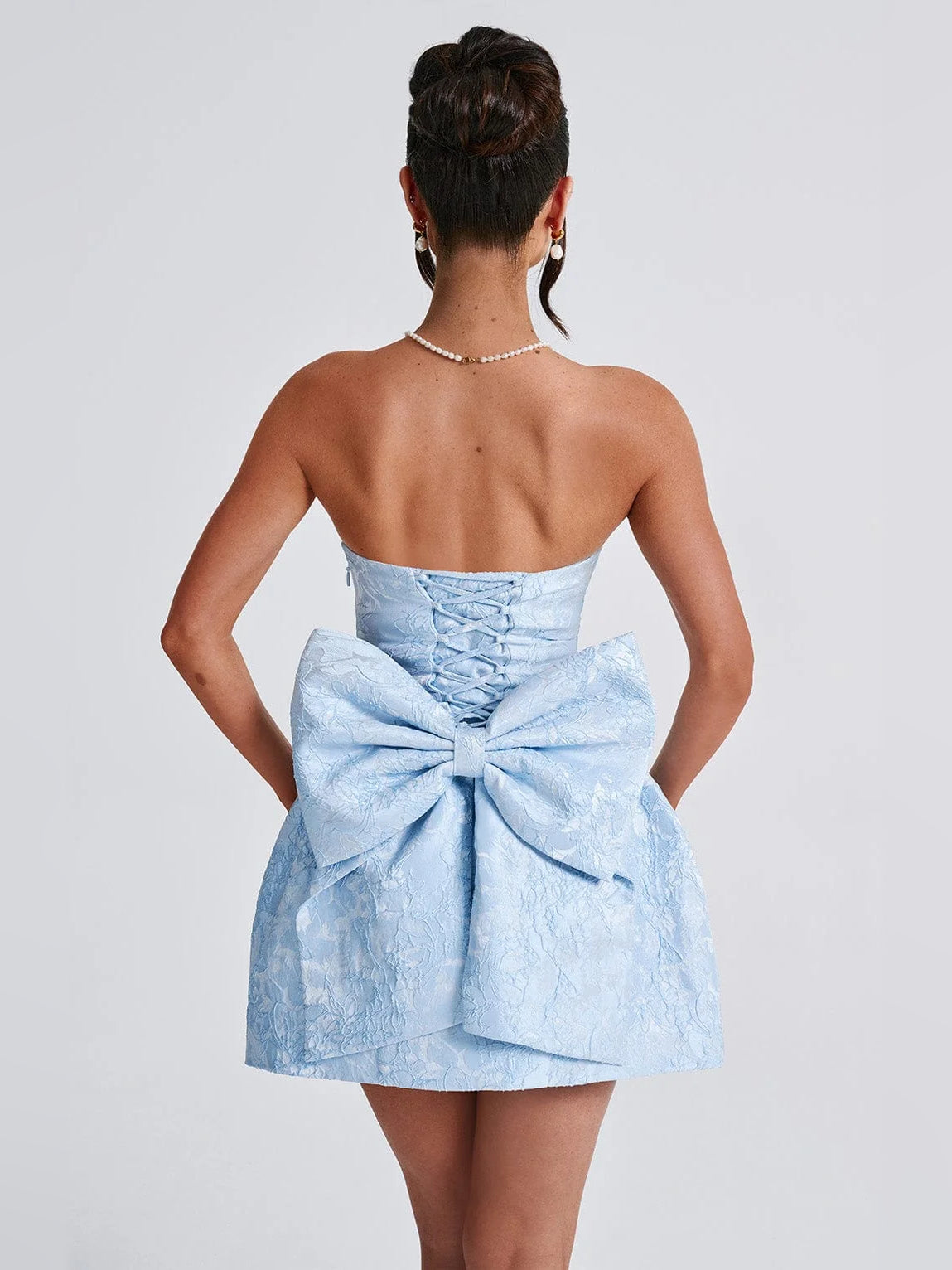Back view of blue strapless mini dress with corset lacing and ruched waist bow.