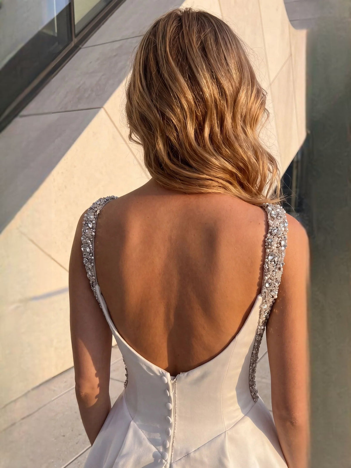 White satin A-line wedding dress with open back and beaded crystal strap edging