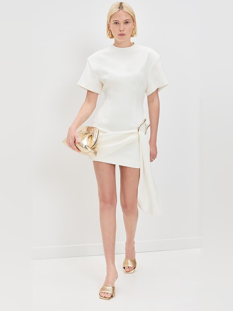 White mini dress with draped front and gold-tone metallic clutch-like handle