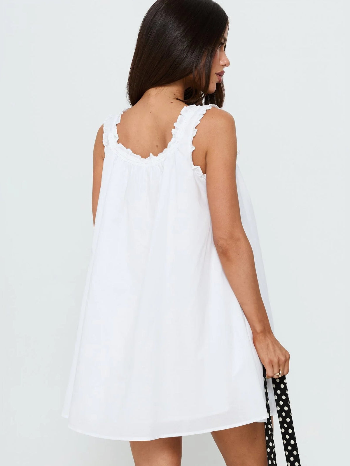 Back view of white mini dress with ruffled straps and gathered tie-back waist