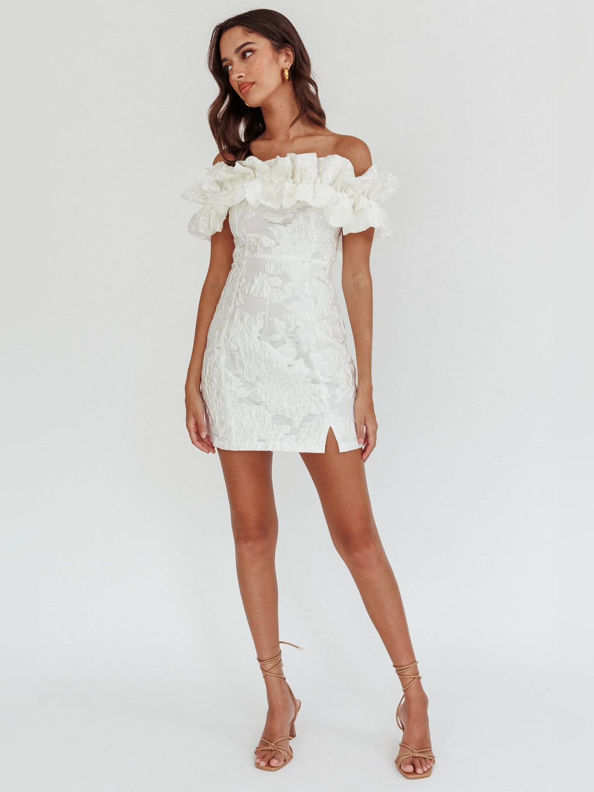 White off-shoulder mini dress with ruffle neckline, textured fabric, side slit, strappy heels