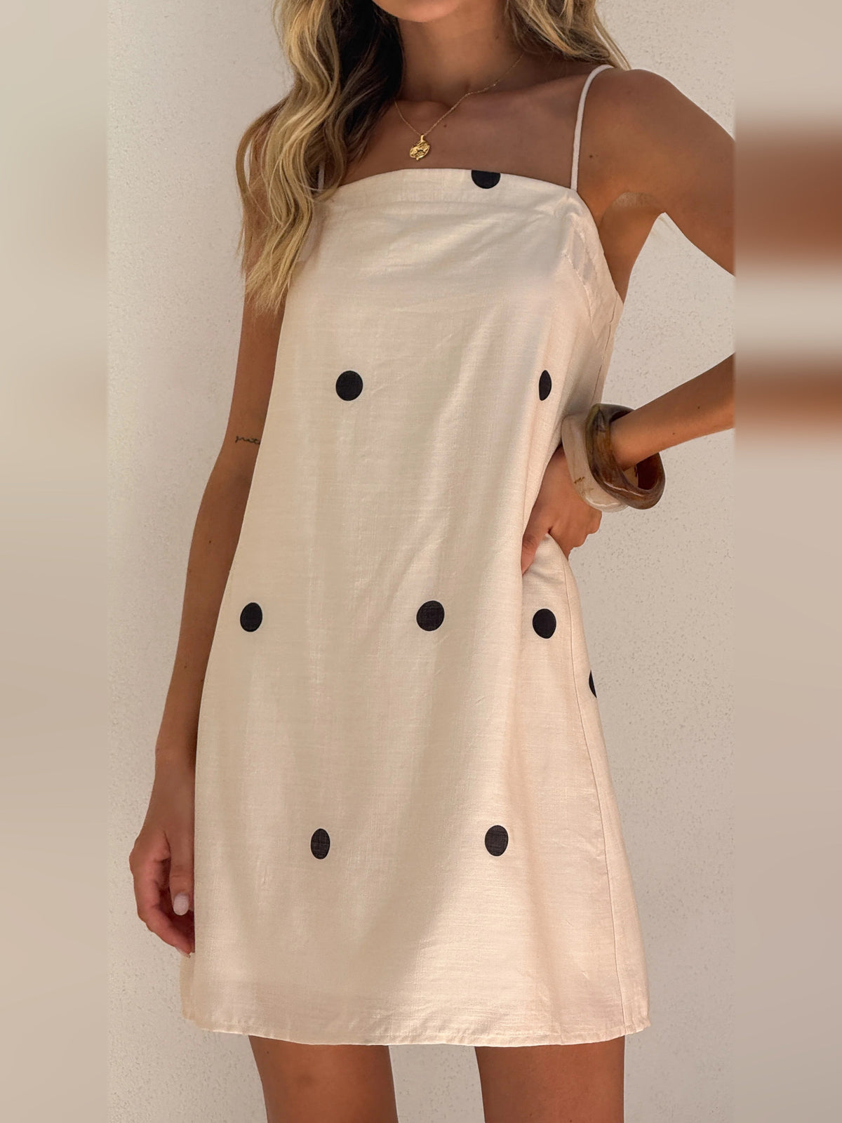 Cream mini dress with black polka dots, adjustable spaghetti straps and fitted bodice