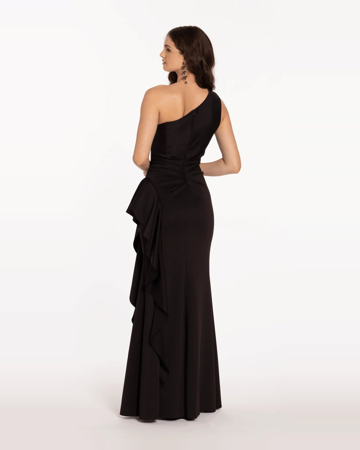 Black one-shoulder trumpet maxi dress with open back and layered ruffle skirt panel