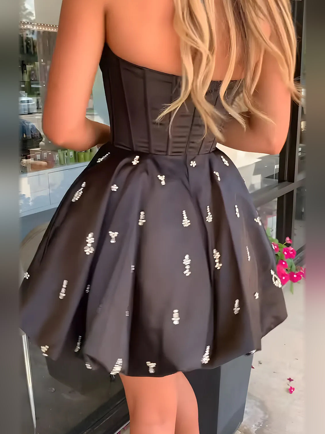 Black satin mini dress close-up: corset bodice and full skirt with small crystal motifs