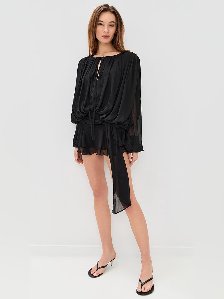 Black mini dress with draped front, long sheer sleeves, and flowing side tie detail