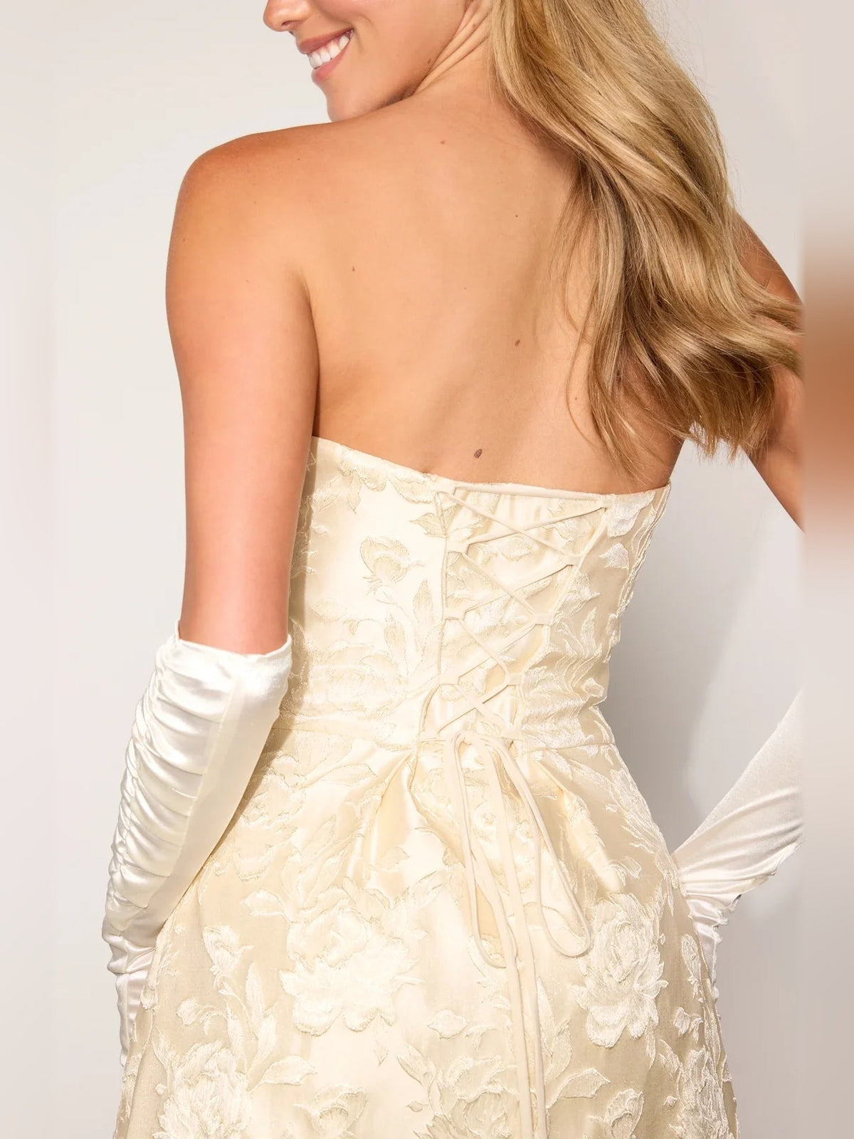 Backless-style view of light gold corset mini dress with floral texture
