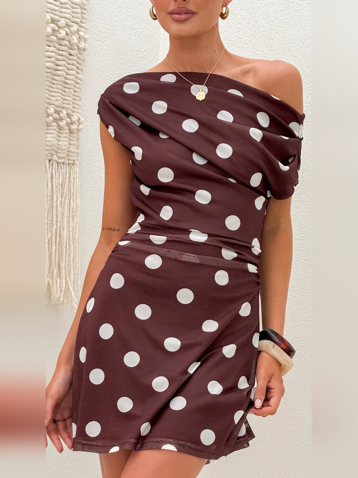 Close-up of brown off-shoulder mini dress with white polka dots and gathered neckline.