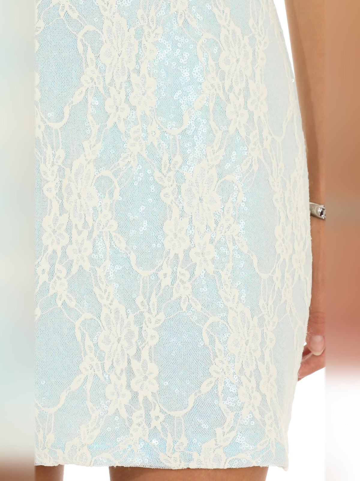 Light blue lace overlay on strapless mini dress, close-up of floral texture.