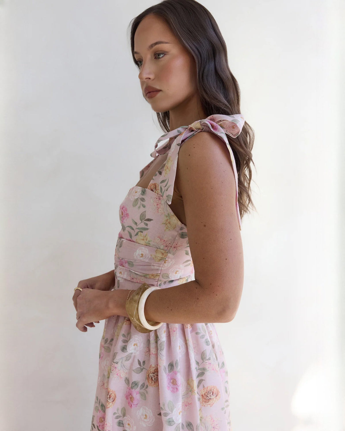 Pink floral satin dress close-up showing tied bow shoulder straps and fitted bodice