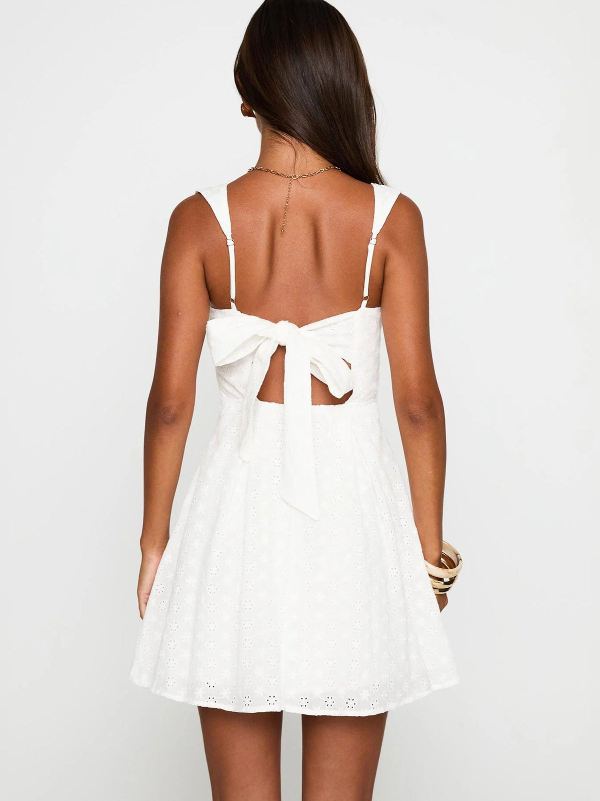 White embroidered mini dress, low back with crossed straps and waist bow
