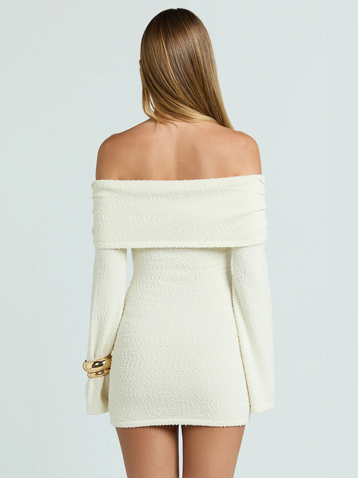 Cream off-shoulder mini dress shown from back with long sleeves and textured fabric