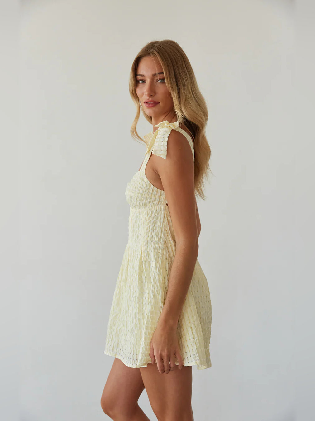 Cream mini dress side view with thin straps and subtle textured fabric