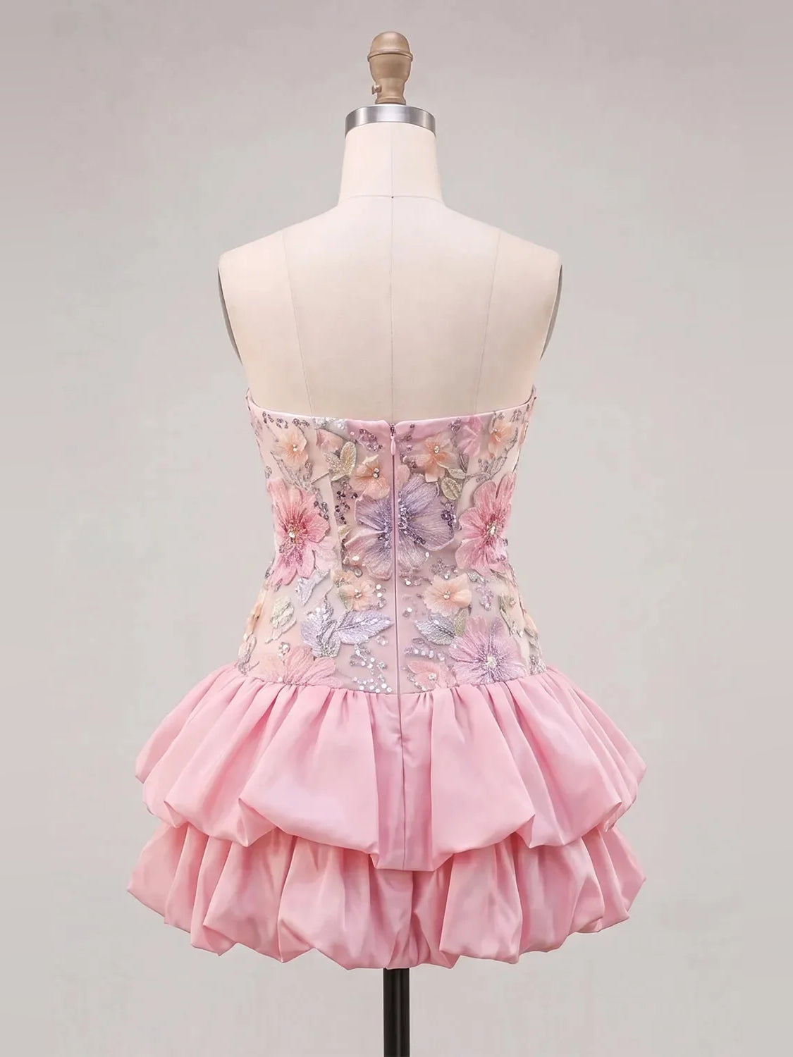 Back view of pink floral strapless mini dress on mannequin with layered ruffle skirt