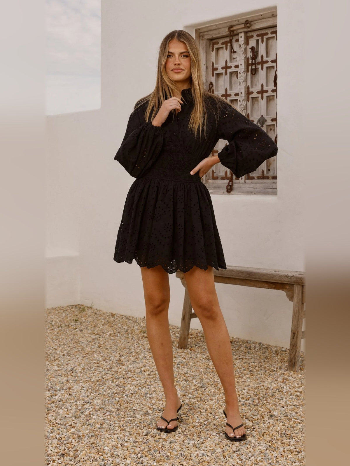 Black long-sleeve mini dress front view, button details, smocked waist, short flared skirt