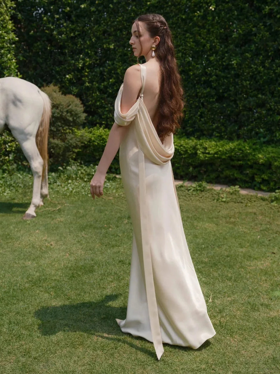 Ivory satin back view of draped cowl neck wedding dress with long flowing skirt