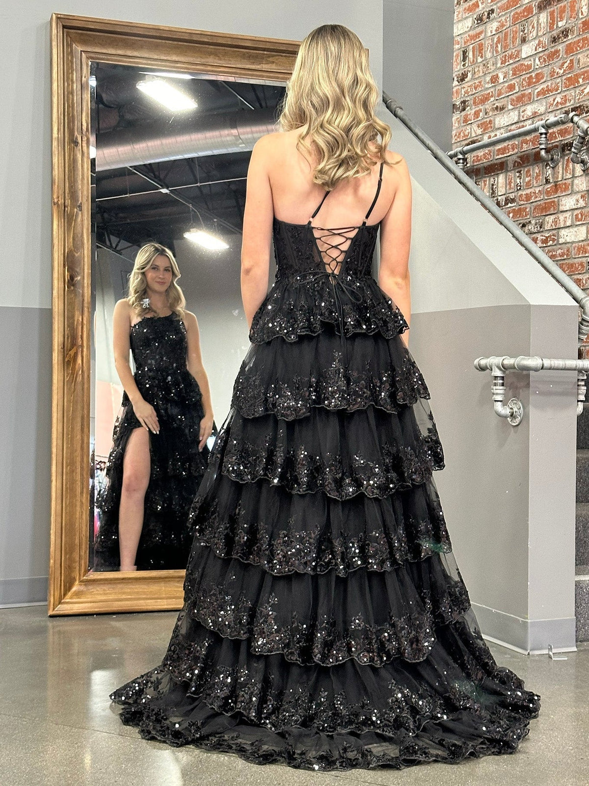 Black corset-style maxi prom dress with tiered tulle skirt and open lace-up back