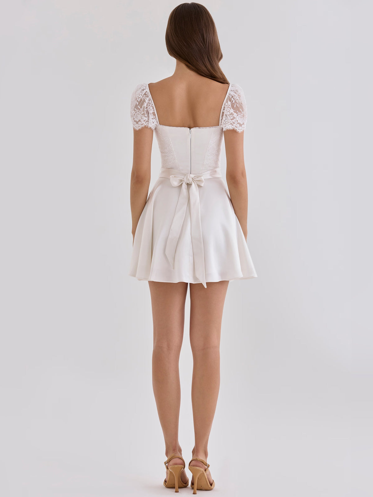 White mini satin homecoming dress with lace cap sleeves, open back, and bow detail