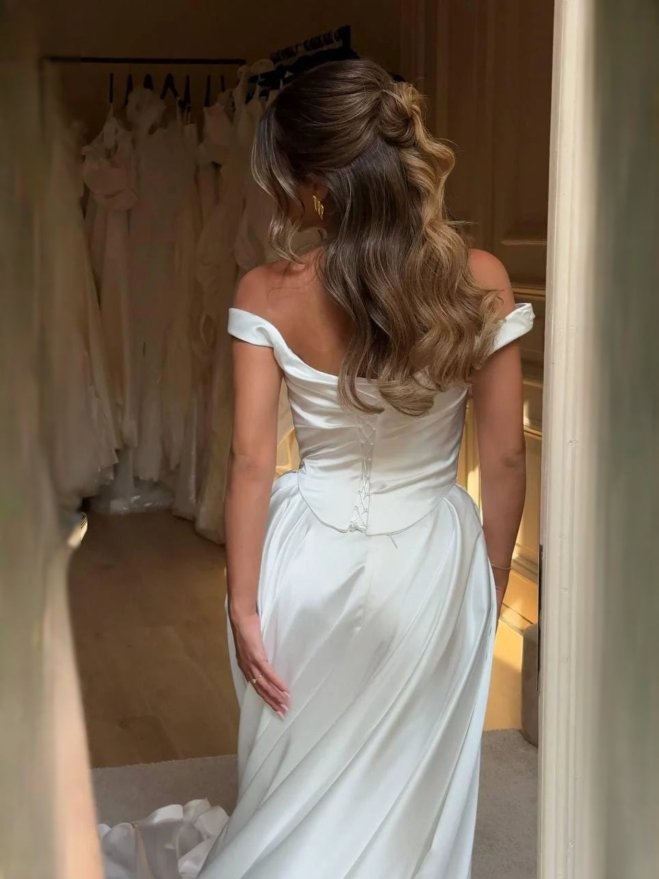 Ivory satin A-line wedding dress from the back with draped corset and off-shoulder neckline