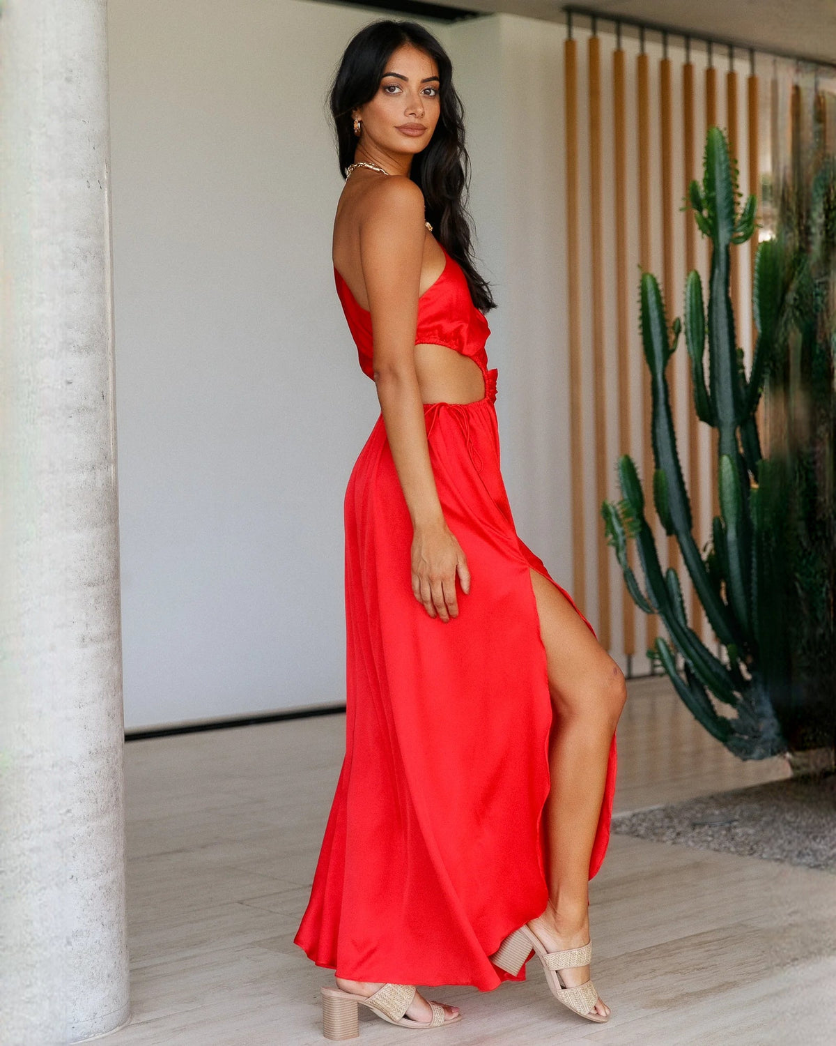 Red satin sleeveless maxi bridesmaid dress with side slit and draped waist knot.