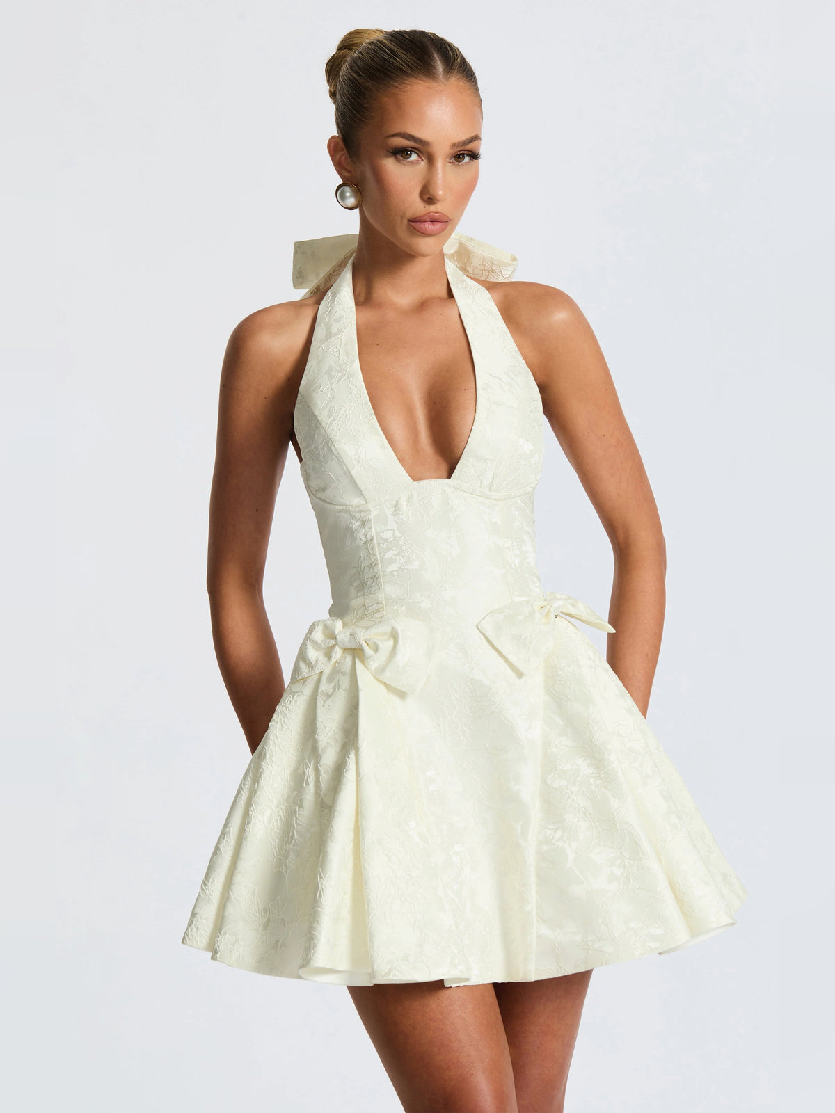 Ivory halter mini homecoming dress with bow detail and full, pleated skirt