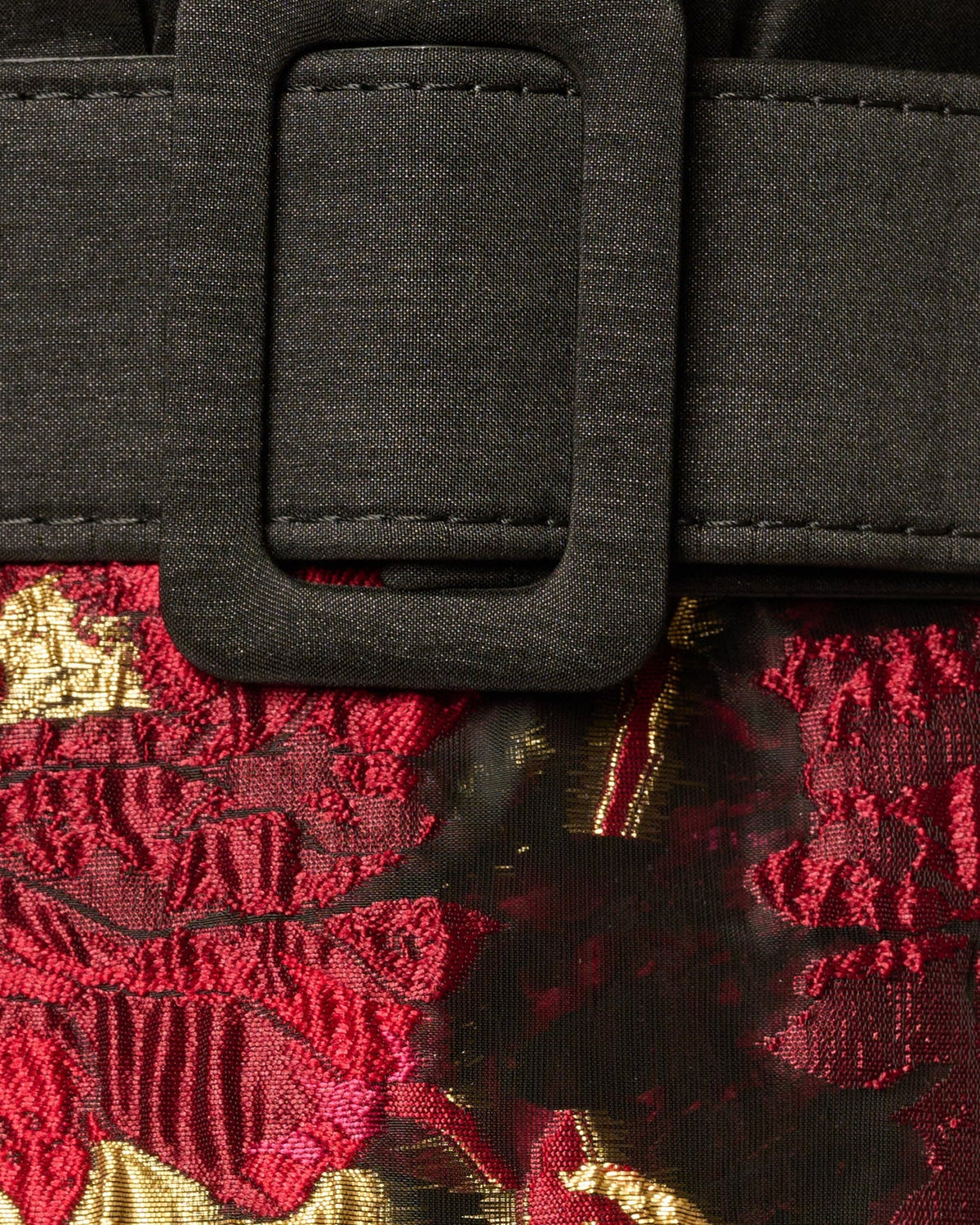 Belted waist detail with black fabric and magenta floral skirt with gold accents