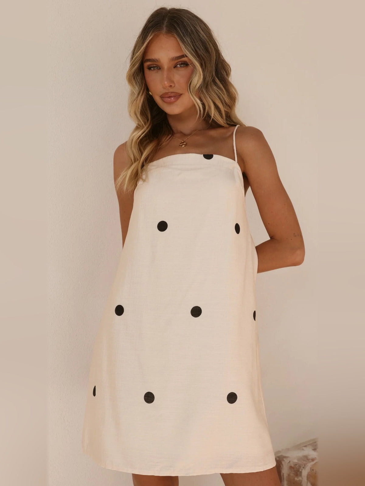 Cream mini dress with black polka dots, spaghetti straps and draped skirt front