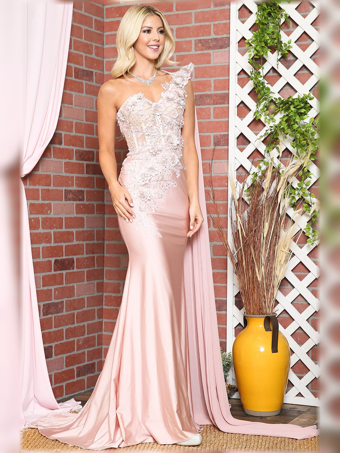 One-shoulder mermaid formal dress in blush pink with floral lace detail and sweeping train.