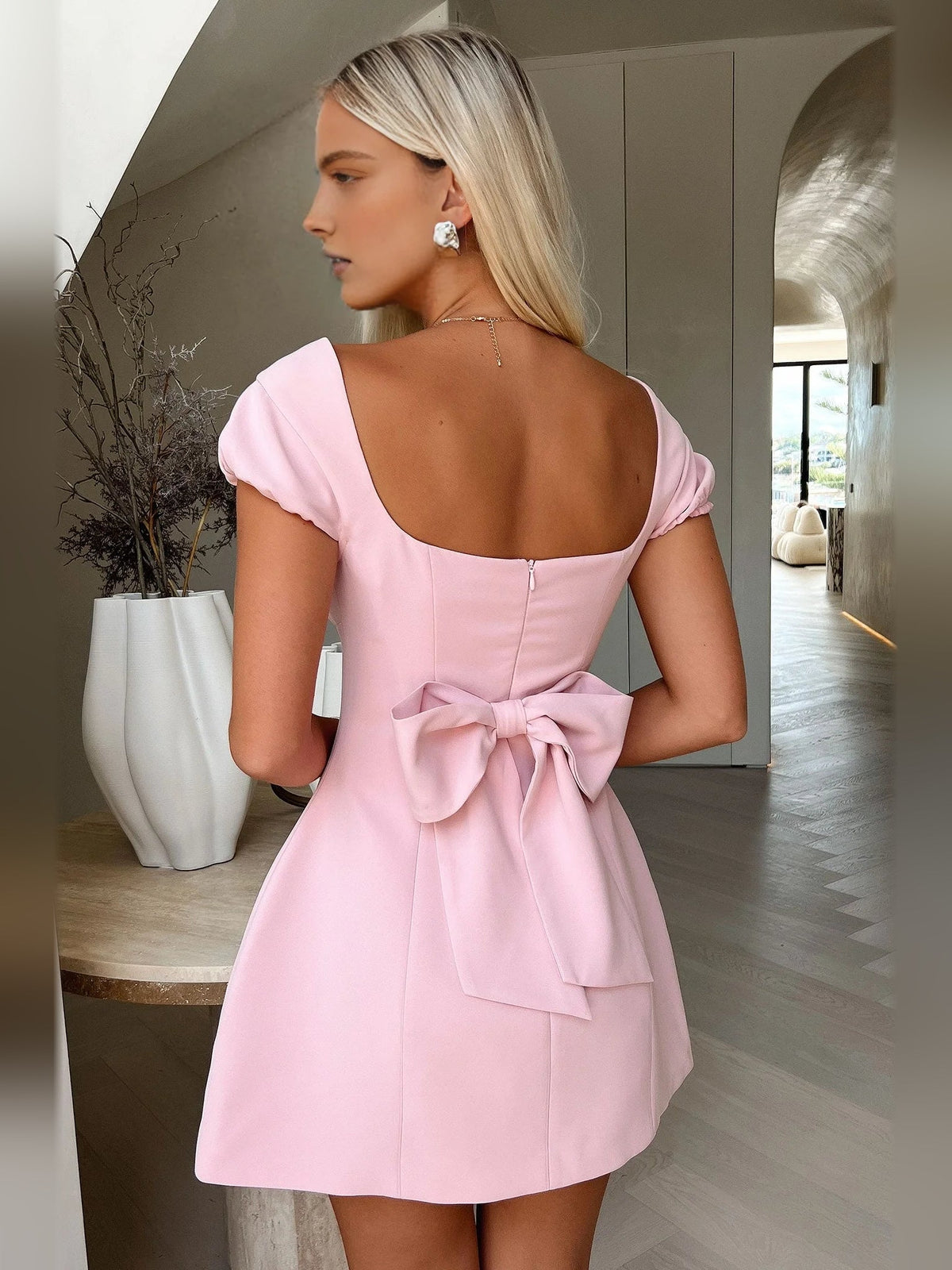 Blush pink back of A-line mini dress with square neckline and large bow at waist