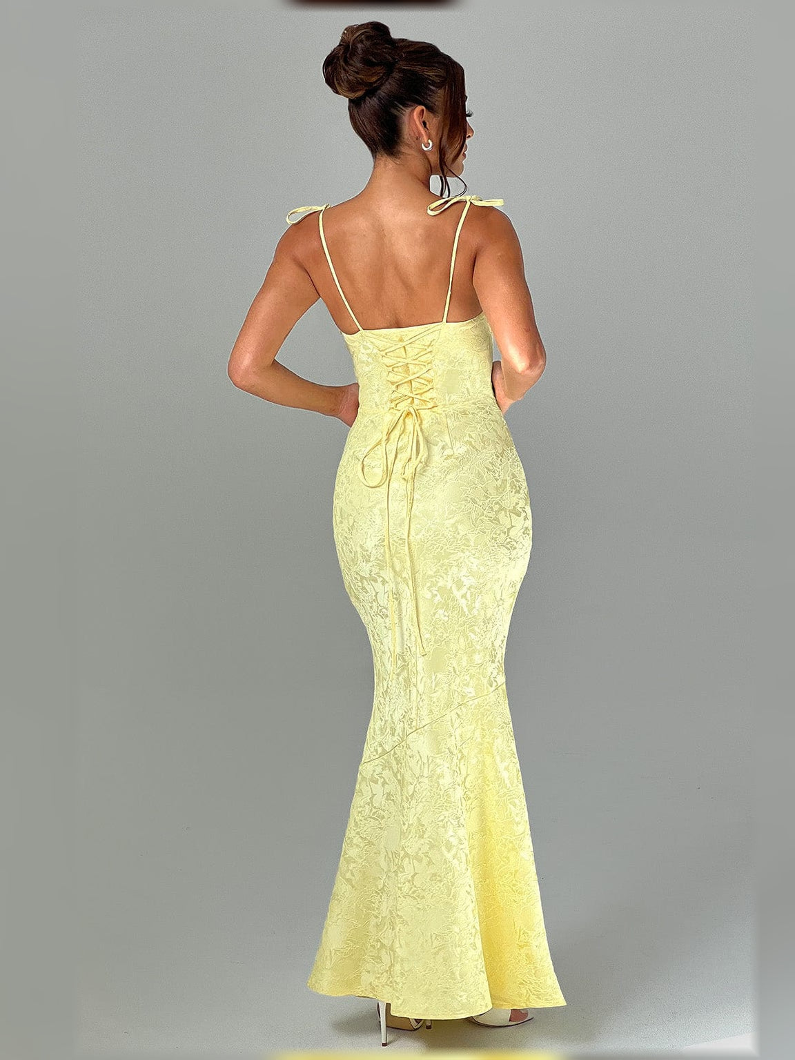 Yellow floral formal dress from back view with lace-up tie details and spaghetti straps