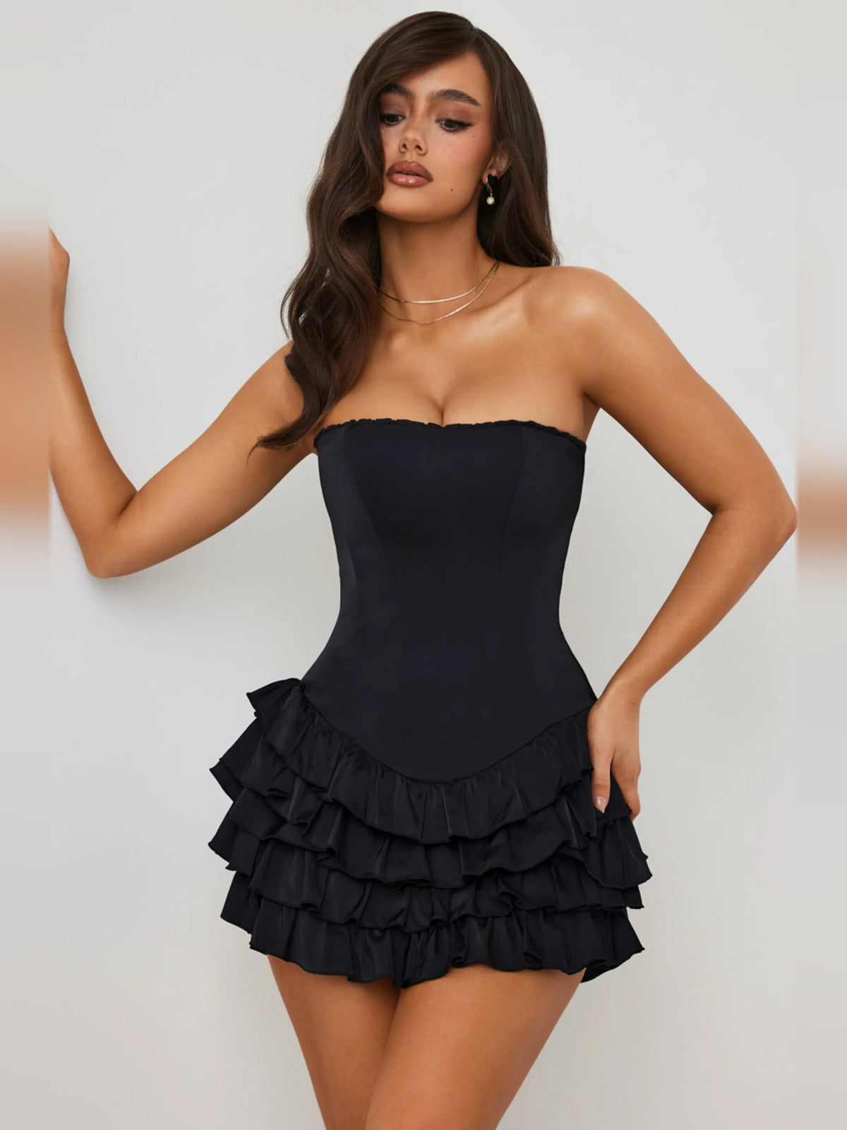 Black strapless corset mini dress with tiered ruffle skirt; fitted bodice and layered hem.