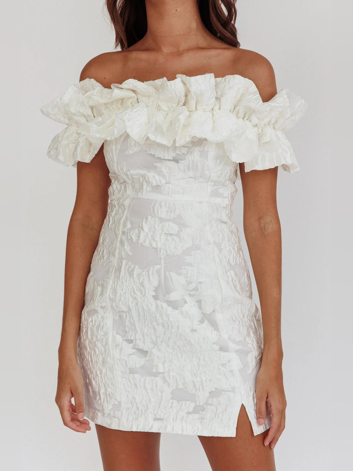 White off-shoulder mini dress with layered ruffle neckline and textured skirt with side slit