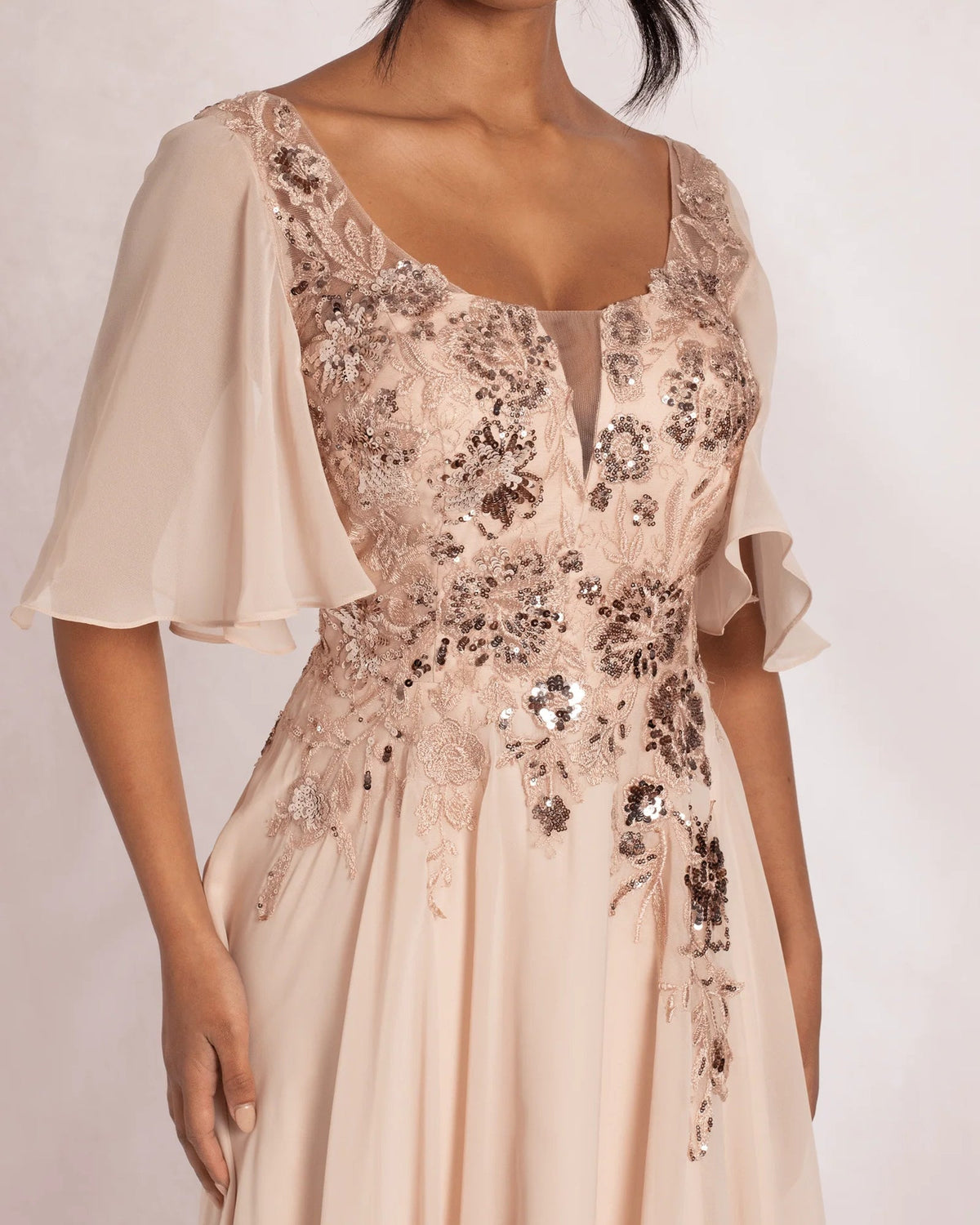 Close-up of blush sequin embroidery on scoop neck bodice with short flutter sleeves