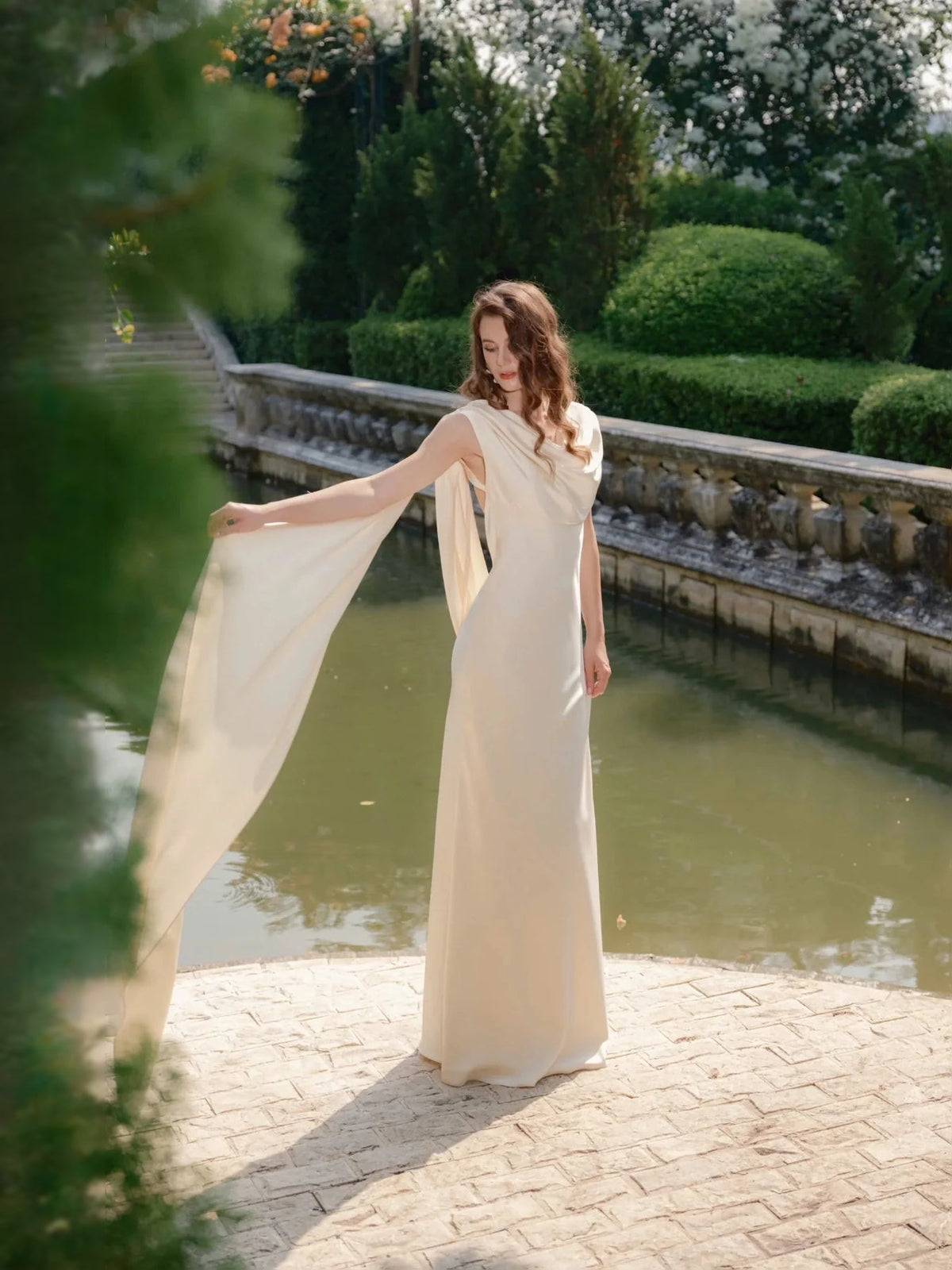Ivory satin sheath wedding dress with draped neckline and long flowing train