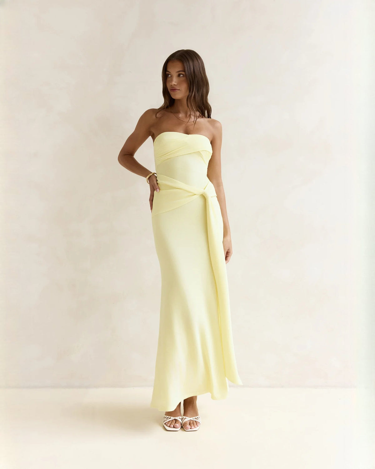 Light yellow strapless satin maxi dress with draped waist, fitted bodice and flared skirt