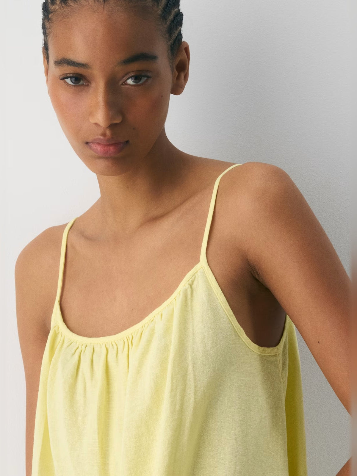 Close-up of light yellow mini dress neckline with thin straps and gathered chest panel