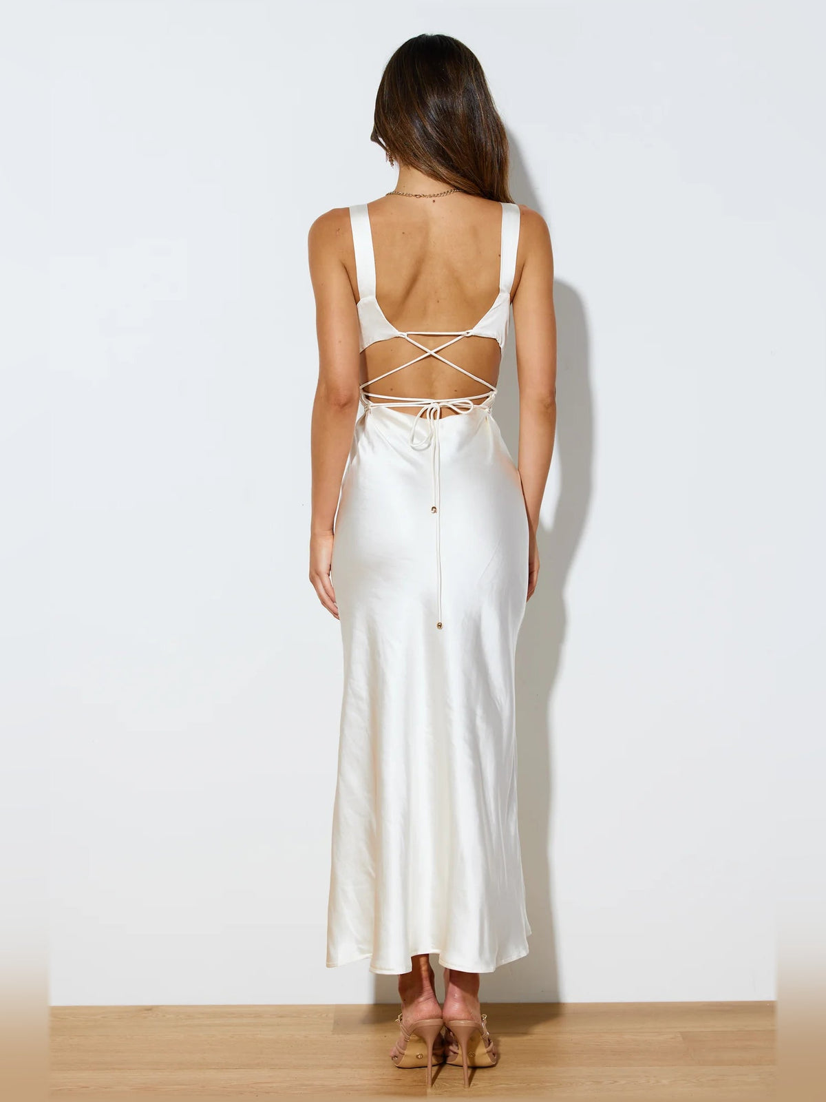 Cream midi formal dress back view with crisscross strap ties and flowing satin skirt