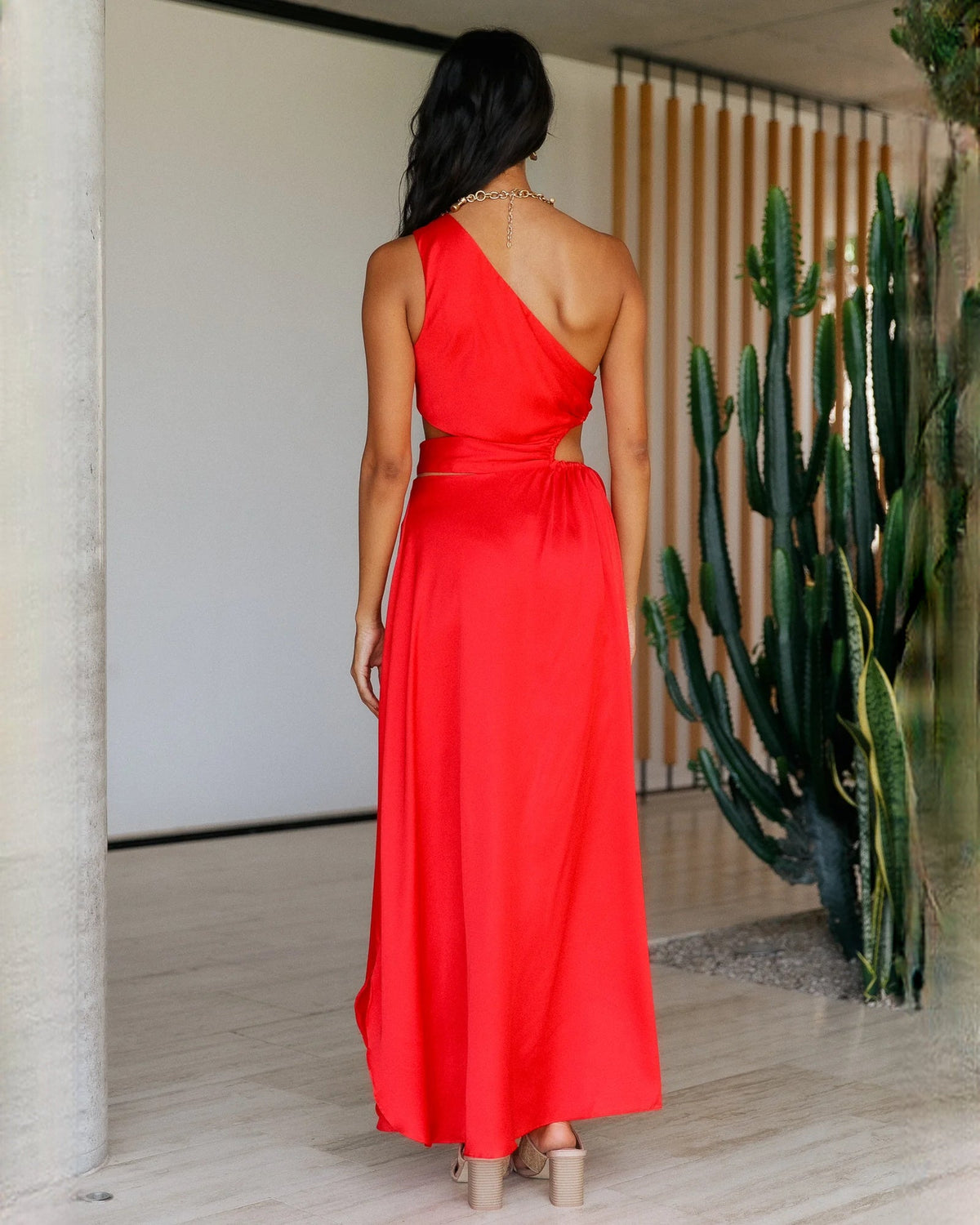 Back view of red satin sleeveless A-line maxi bridesmaid dress with draped waist detail.