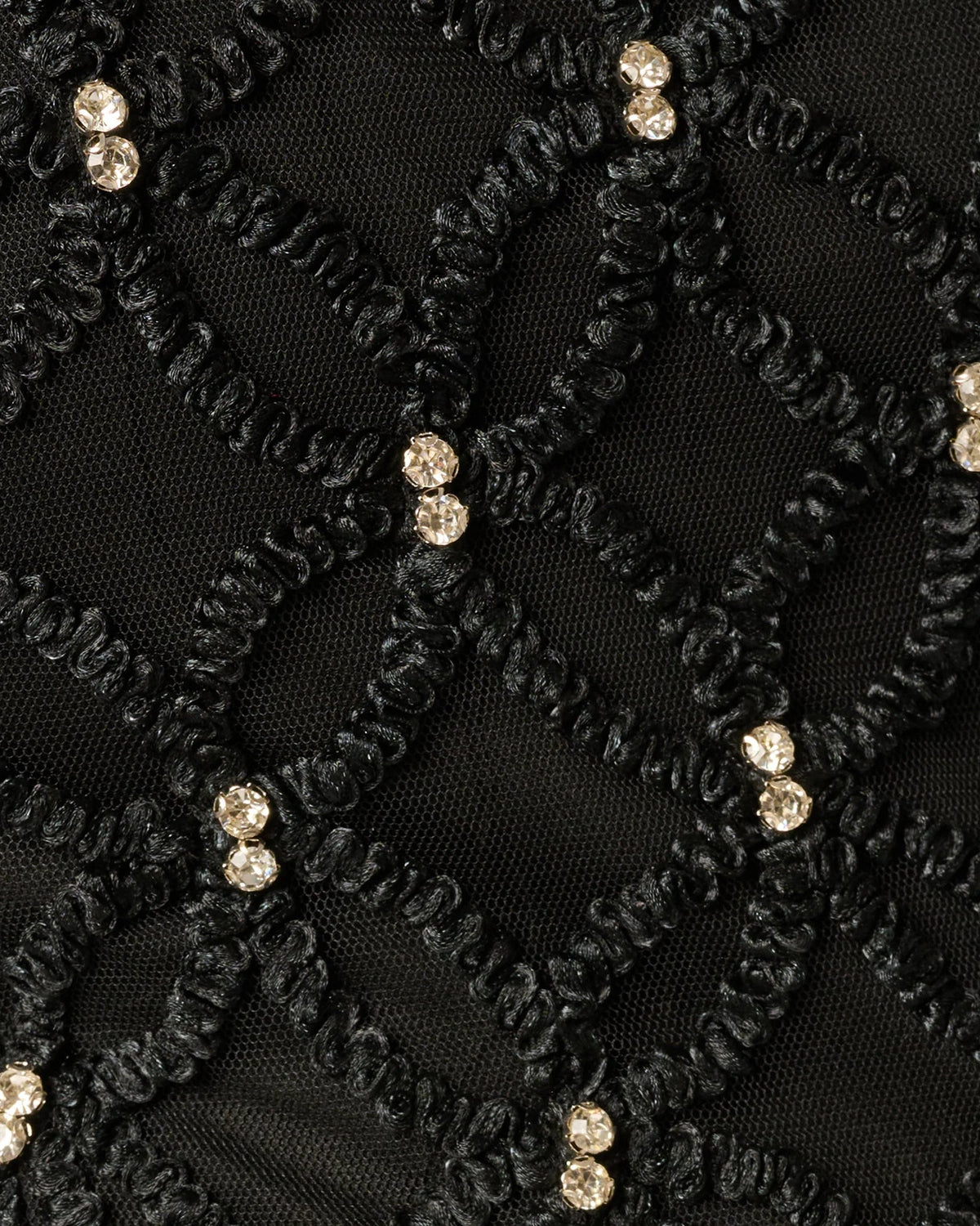 Close-up of black lace with gold bead accents in a diamond pattern