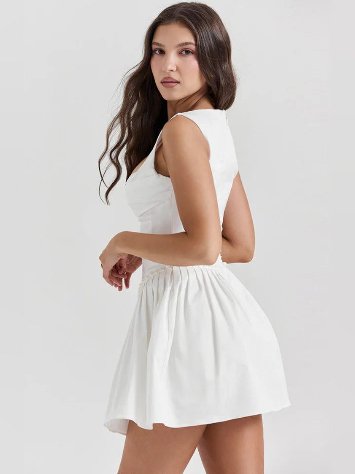 White pleated mini dress in back/side view with sleeveless bodice
