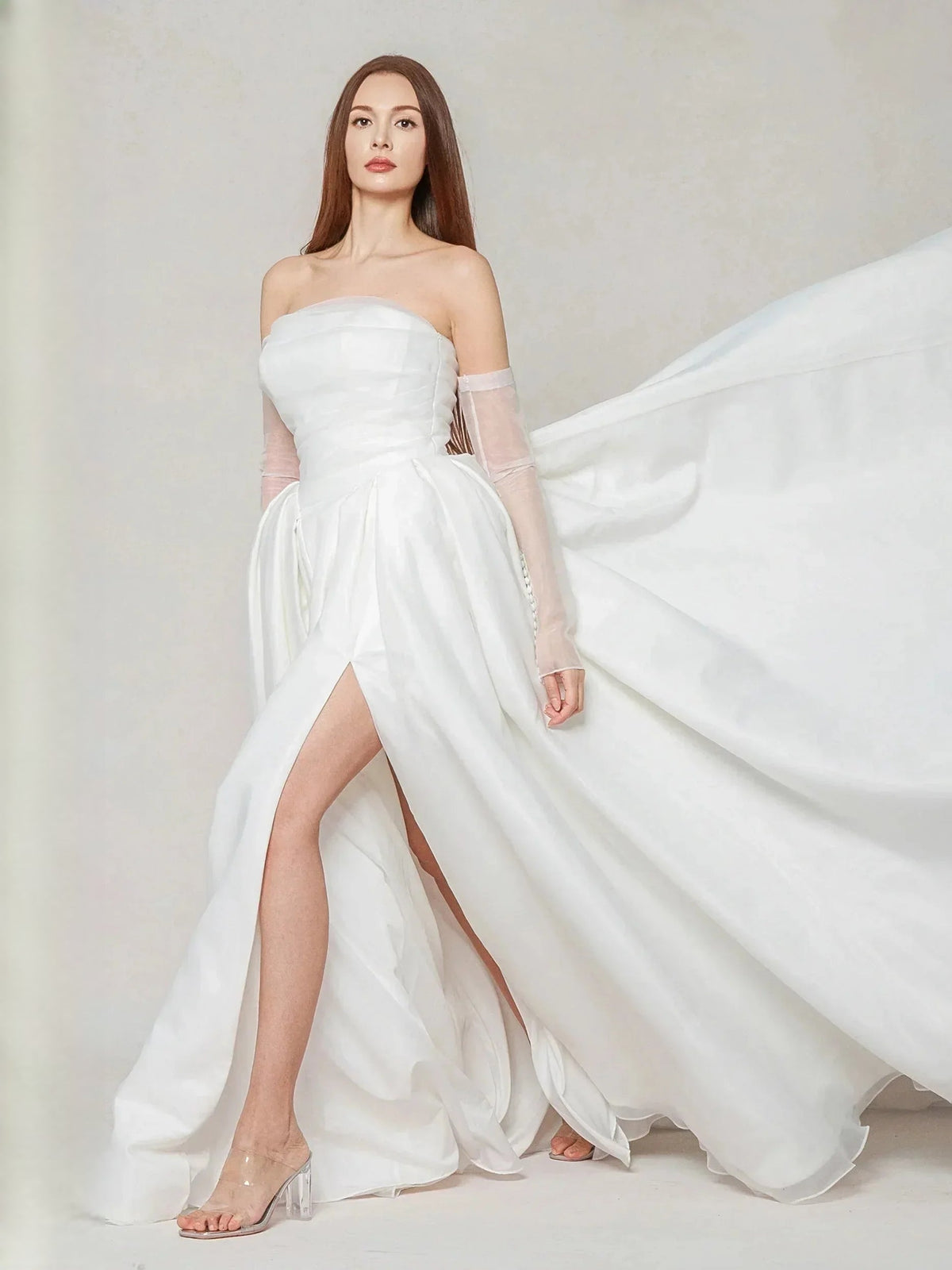 Ivory strapless wedding dress side view with pleats, dramatic side slit, and trailing train