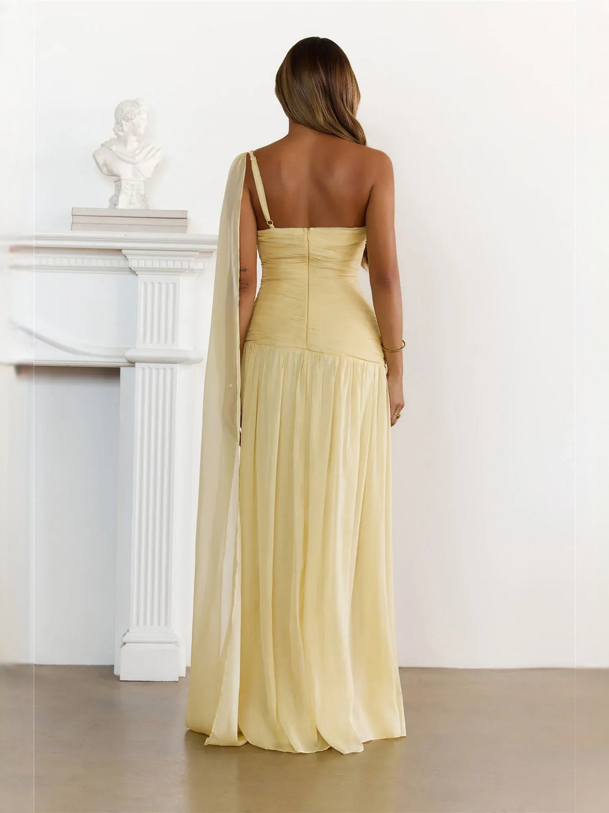 Pale yellow one-shoulder ruched maxi dress, back view with tulle drape and gathered skirt