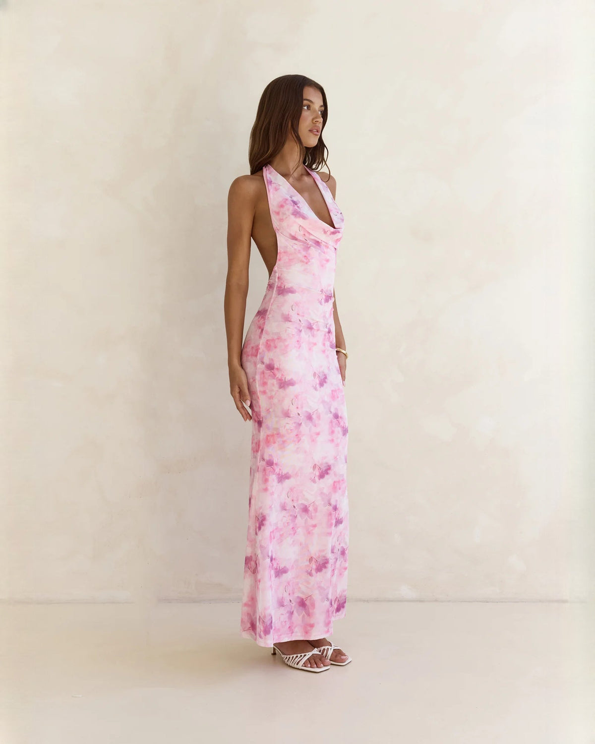 Pink floral halter neck maxi dress in side view with open back detail