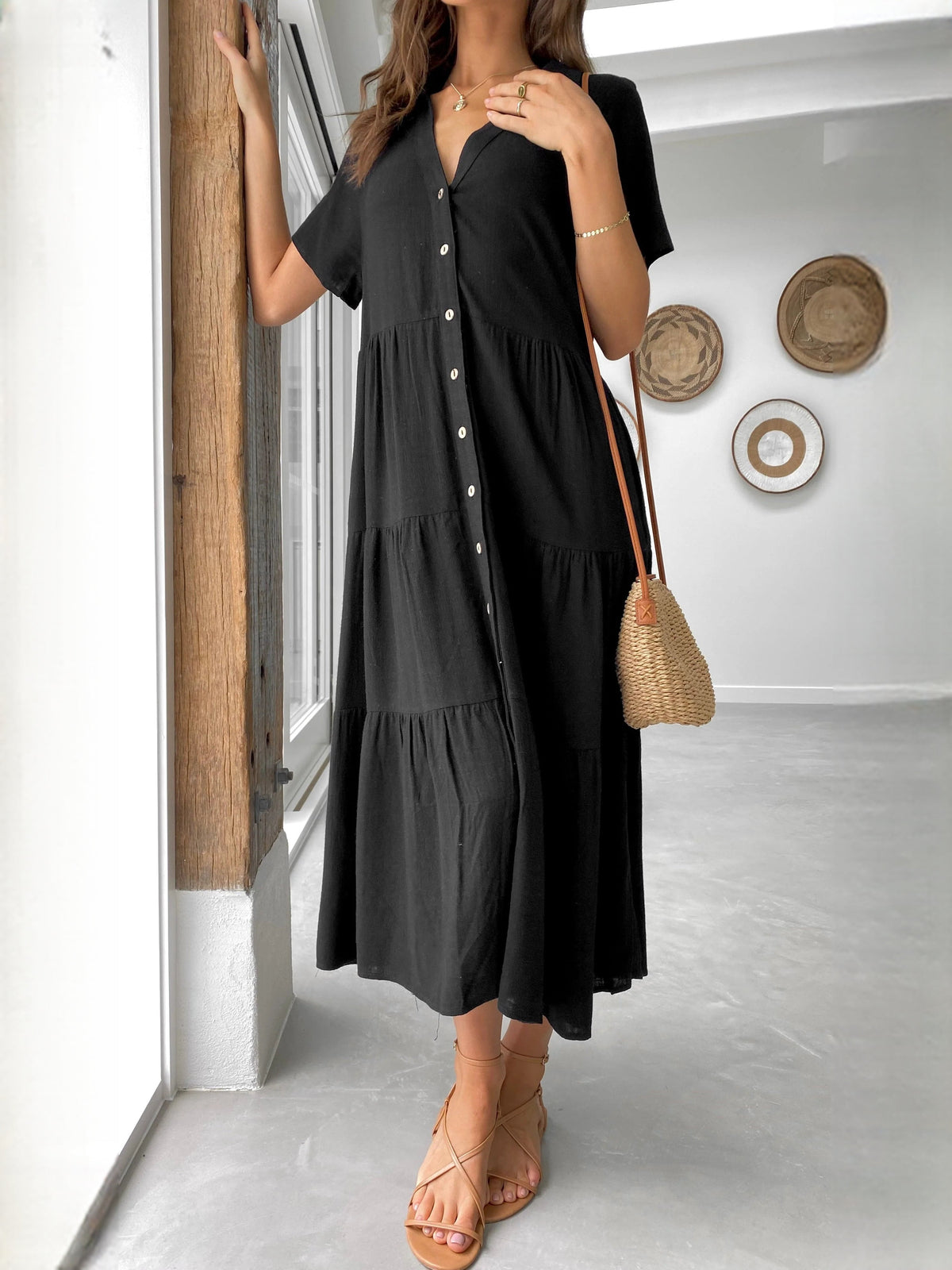 Close-up of black midi dress: V-neck, short sleeves, button-front, tiered skirt layers
