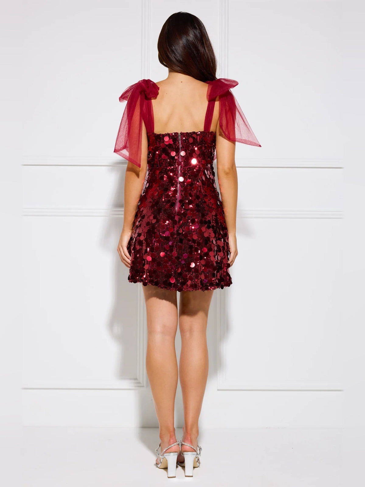 Red sequin mini dress from back view, sheer bow straps and open back
